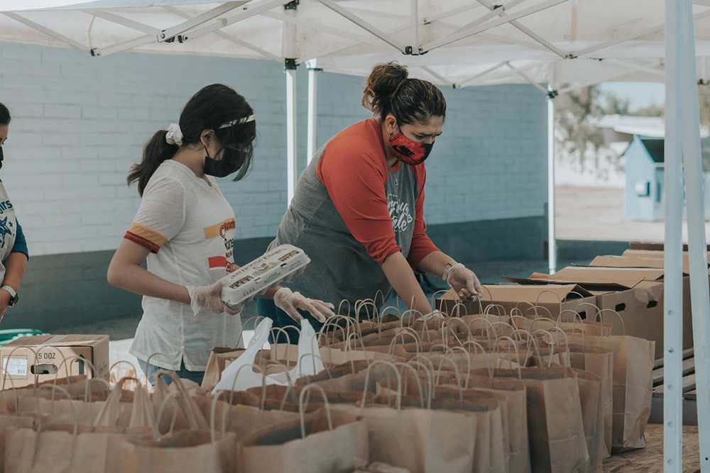 two women volunteering and packing food bags