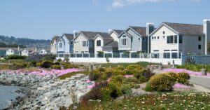 Senior manufactured home community filled with adjacent houses. Pink flowers and a lake fill the landscape.