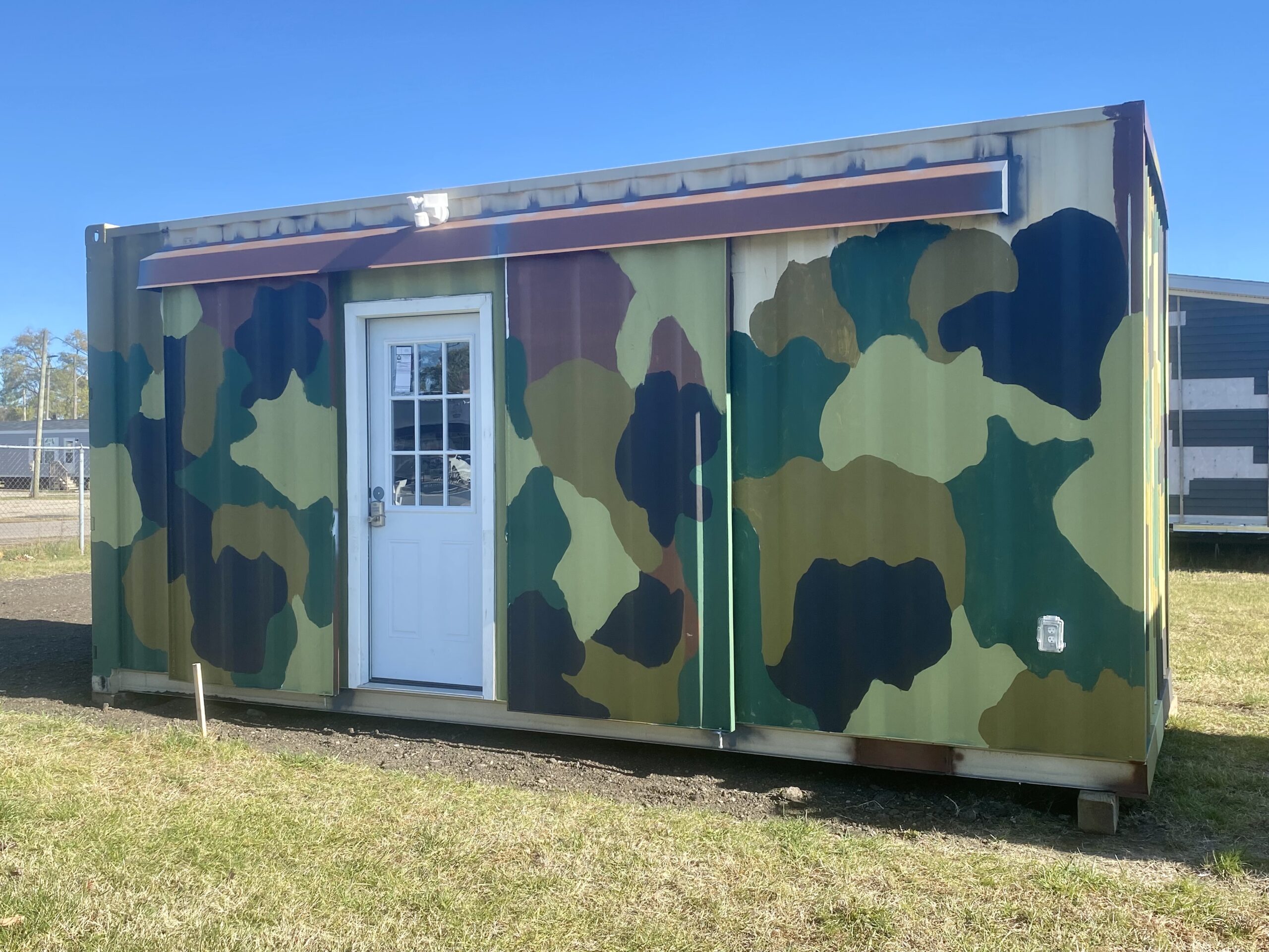 Camouflage patterned shipping container hunting lodge with a front door
